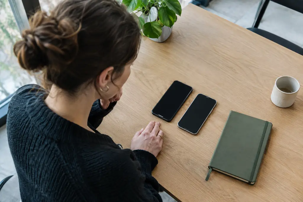 Deux téléphones aux écrans éteints sont posés côte à côte dans un espace de travail.